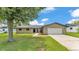 Inviting single-story home featuring a well-manicured lawn, mature tree, and attached two-car garage at 4622 Grovecrest Dr, Lakeland, FL 33813