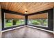 Cozy sunroom features wood ceiling, dark walls, wood-look flooring, and lots of natural light at 504 Prado Pl, Lakeland, FL 33803