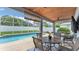 This screened patio features a wood plank ceiling, a mounted flatscreen tv, and overlooks the crystal blue in-ground swimming pool at 5579 Summerland Hills Dr, Lakeland, FL 33812