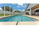 This in-ground swimming pool features a screened enclosure and adjoins a covered patio with tv and outdoor furniture at 5579 Summerland Hills Dr, Lakeland, FL 33812
