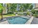 Backyard pool featuring stone surround, a manicured lawn, privacy fence and lush landscaping at 608 Finney St, Lakeland, FL 33803