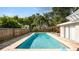 Sparkling pool surrounded by a wood fence, lush greenery, and tropical palm trees at 6421 Calusa Dr, Lakeland, FL 33813
