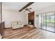 Living room showcases a fireplace, wood floors, ceiling fan, seating, and sliding glass doors to a sunroom at 849 Rockingham Rd, Lakeland, FL 33809