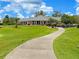 Golf clubhouse with a scenic pathway, well-manicured lawns, and parked golf carts at 9017 Se 119Th St, Summerfield, FL 34491