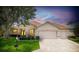 Charming single-story home with a well-manicured lawn, three-car garage, and a neatly landscaped front yard at sunset at 9017 Se 119Th St, Summerfield, FL 34491