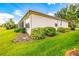 A side view of a well-maintained beige house with manicured landscaping and a green lawn at 9017 Se 119Th St, Summerfield, FL 34491