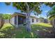 Backyard view featuring a mature tree, well-maintained lawn, and a screened-in porch at 1081 Sunshine Sw Way, Winter Haven, FL 33880