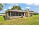 Back view of home showcasing a screened-in porch and spacious yard at 113 W Juliana Way, Auburndale, FL 33823