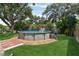 Backyard features a well-maintained lawn, mature trees, landscaping, and an above-ground pool at 1210 Heidi S Ln, Lakeland, FL 33813