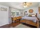 Comfortable bedroom features wood floors, ceiling fan, and natural light from the large window at 1210 Heidi S Ln, Lakeland, FL 33813