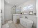 Bright bathroom featuring a glass shower and tub with decor and natural light from the window at 128 Melissa Trl, Auburndale, FL 33823