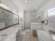 Spacious bathroom featuring dual sinks, a glass shower, a soaking tub, and stylish wood-look tile floors at 128 Melissa Trl, Auburndale, FL 33823