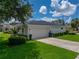 Features of a spacious two-car garage, concrete driveway, lush lawn and manicured landscaping at 128 Melissa Trl, Auburndale, FL 33823