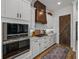 Modern kitchen featuring stainless steel appliances, white cabinets, and custom wooden range hood at 128 Melissa Trl, Auburndale, FL 33823