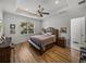 Serene main bedroom features tray ceiling, a ceiling fan, wood floors, and a peaceful ambiance at 128 Melissa Trl, Auburndale, FL 33823