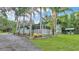 Charming single-story home featuring a welcoming porch, palm trees, and lush landscaping at 15345 Angus Rd, Polk City, FL 33868