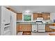 Well-lit kitchen with white appliances, wood cabinets, and a view of the outdoors at 15345 Angus Rd, Polk City, FL 33868