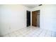 Bright bedroom features white tile flooring and an open closet with natural wood door at 1720 Park Dr, Lakeland, FL 33803