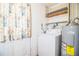 A functional laundry room featuring a washing machine, water heater, storage shelves, and door with floral curtain at 1720 Park Dr, Lakeland, FL 33803