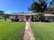 Charming single-story home with a well-maintained lawn and a inviting red front door at 2105 E Cherokee St, Bartow, FL 33830