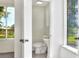 Bright half-bathroom featuring a pedestal sink, white toilet, and privacy window to the outdoors at 215 W Valencia St, Lakeland, FL 33805