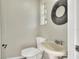 This half-bath has a pedestal sink, toilet, decorative mirror, and a window letting in natural light at 215 W Valencia St, Lakeland, FL 33805