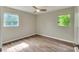 A standard bedroom featuring two jalousie windows, a ceiling fan, and wood-look vinyl flooring at 215 W Valencia St, Lakeland, FL 33805