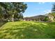 Expansive backyard featuring lush green grass, large trees, and a screened-in patio at 2208 Deerbrook Dr, Lakeland, FL 33811