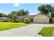 Well-maintained single-story home with a long driveway and attached garage, surrounded by lush green lawn and mature landscaping at 2208 Deerbrook Dr, Lakeland, FL 33811