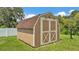 Charming storage shed with brown siding, white trim, and a shingled roof in backyard at 2932 Blackwater Oaks Dr, Mulberry, FL 33860