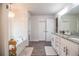 Bright bathroom with white cabinets, double vanity, soaking tub and wood-look tile flooring at 4222 Juliana Lake Dr, Auburndale, FL 33823