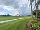 View of the golf course framed by palm trees and lush landscaping under a dramatic sky at 443 Enclave Pl # 0, Lakeland, FL 33803