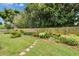 Large backyard featuring healthy green grass, stepping stones, and lush plantings at 451 Village Sw Cir, Winter Haven, FL 33880