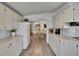 Open kitchen showcases white cabinets, appliances, and laminate flooring, offering a clean and functional space at 451 Village Sw Cir, Winter Haven, FL 33880
