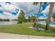 Scenic community pool overlooking a serene lake with a comfortable bench and lush landscaping at 451 Village Sw Cir, Winter Haven, FL 33880
