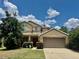 Inviting two-story home featuring a well-manicured lawn, mature trees, and a neutral color scheme under a sunny blue sky at 4665 Sw 40Th Pl, Ocala, FL 34474