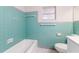Bathroom with turquoise tile and modern fixtures including a toilet, tub, and window at 508 Boger N Blvd, Lakeland, FL 33803