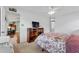 Light-filled bedroom featuring a floral comforter, ceiling fan, and a wooden bookshelf with a television at 5771 Macaw Pl, Lakeland, FL 33809
