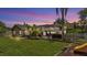 Scenic backyard with a screened-in pool, playset, and manicured lawn at twilight at 5819 Hollyhock Dr, Lakeland, FL 33813