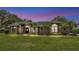 Beautiful home with lush landscaping, mature palms, and manicured lawn at dusk at 5819 Hollyhock Dr, Lakeland, FL 33813