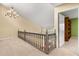 Upstairs hallway with neutral walls, carpet, chandelier and wooden railings at 6033 Mountain Lake Dr, Lakeland, FL 33813