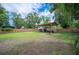 Large backyard features a wooden fence, green grass, mature trees, and a metal shed at 615 N Church Ave, Fort Meade, FL 33841