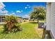 Home exterior featuring tropical plants, a grassy lawn, tree, and air conditioning utility access at 6443 Hollyberry Ne Ln, Winter Haven, FL 33881