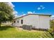 Home exterior showcasing white siding, lush lawn, and utility access with an air conditioning unit at 6443 Hollyberry Ne Ln, Winter Haven, FL 33881