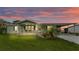 Inviting single-story home featuring a covered porch, well-kept lawn, and a serene sunset backdrop at 6509 Oak Hammock Ct, Winter Haven, FL 33884