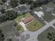 Aerial view of a single-story home with a brown roof, surrounded by lush greenery and neighboring houses at 7150 Orange Way, Lakeland, FL 33810