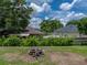Spacious backyard featuring lush greenery, a wood pile, and a partial view of neighboring houses at 7150 Orange Way, Lakeland, FL 33810