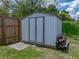 Storage shed in a fenced backyard, complemented by a neat stack of wood on a well-manicured lawn at 7150 Orange Way, Lakeland, FL 33810