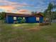 Blue single-story home backyard with a well-kept lawn, landscaping, and a screened-in patio at 7150 Orange Way, Lakeland, FL 33810