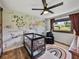 Cozy bedroom with a crib, accent wall featuring animals, and modern ceiling fan at 7150 Orange Way, Lakeland, FL 33810